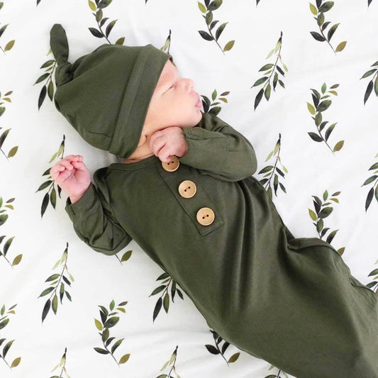 Baby in an olive green outfit with buttons 
