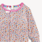A close-up of a long-sleeve children's top with a dense multicolor butterfly print on a white base, featuring a pink ribbed collar and a colorful striped inner neck trim.